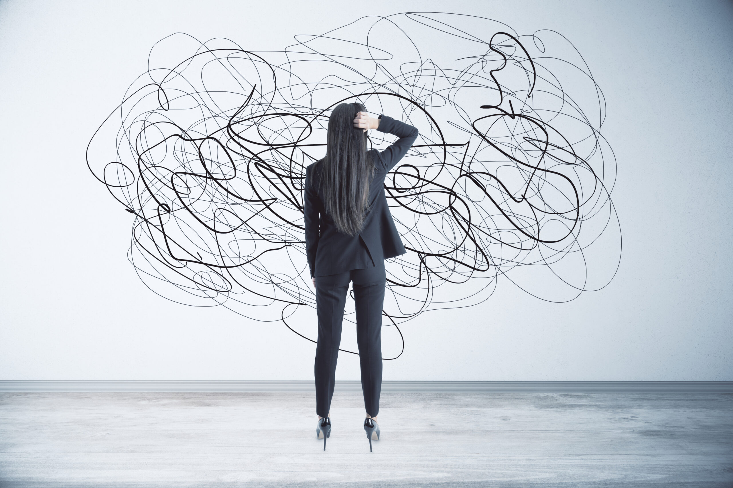 Businesswoman facing a wall of tangled scribbles representing overthinking and mental chaos